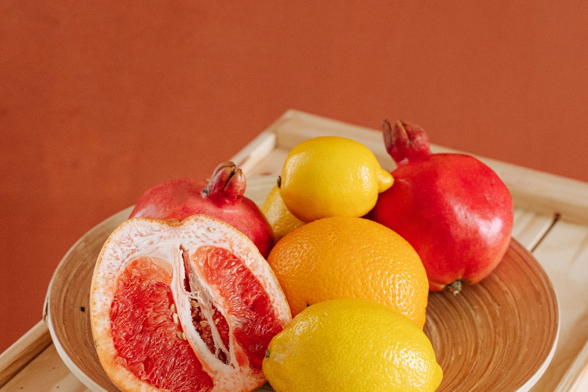 Red And Yellow Citrus Fruits on Brown Plate